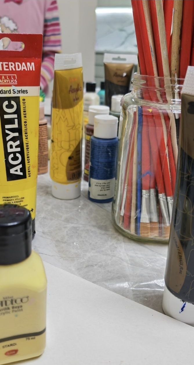 Close-up of paint tubes and a jar of brushes